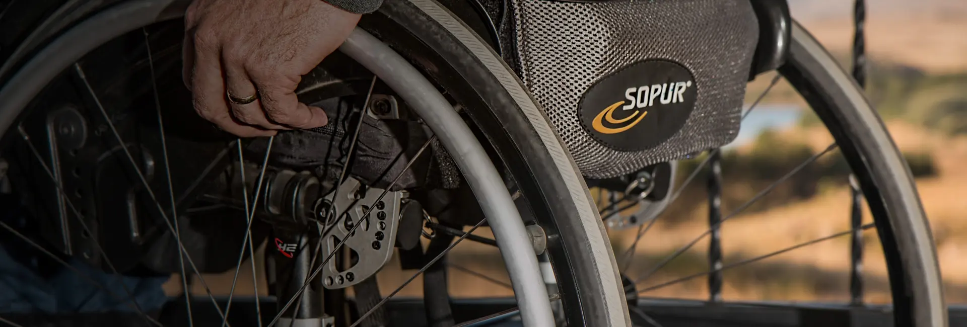 A hand on the wheel rim of a manual wheelchair