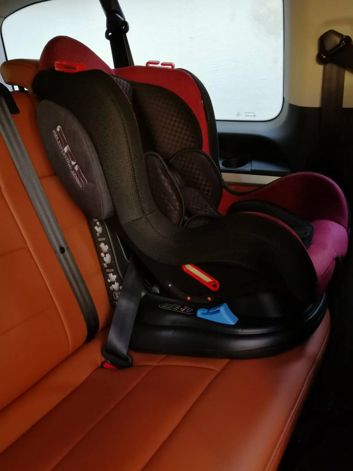 A child seat fitted on the tan leather rear bench of an Attica Transfer mini van
