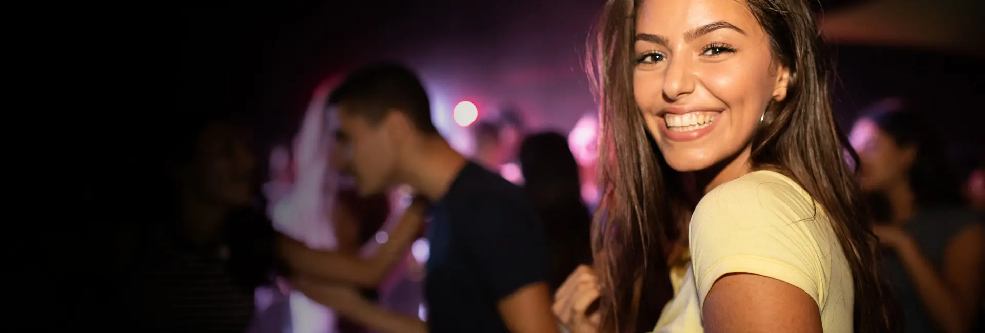 A student smiling among friends on a night out