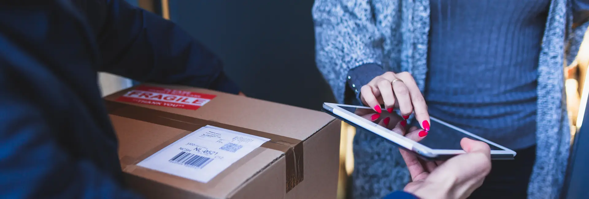 A courier handing over a parcel marked Fragile for signature