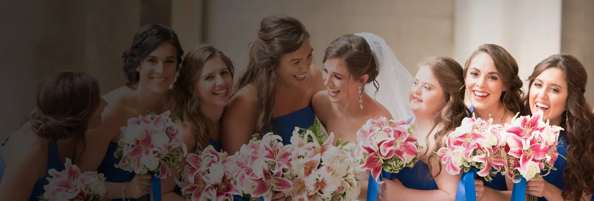 A bride laughing with her bridesmaids, all holding bouquets